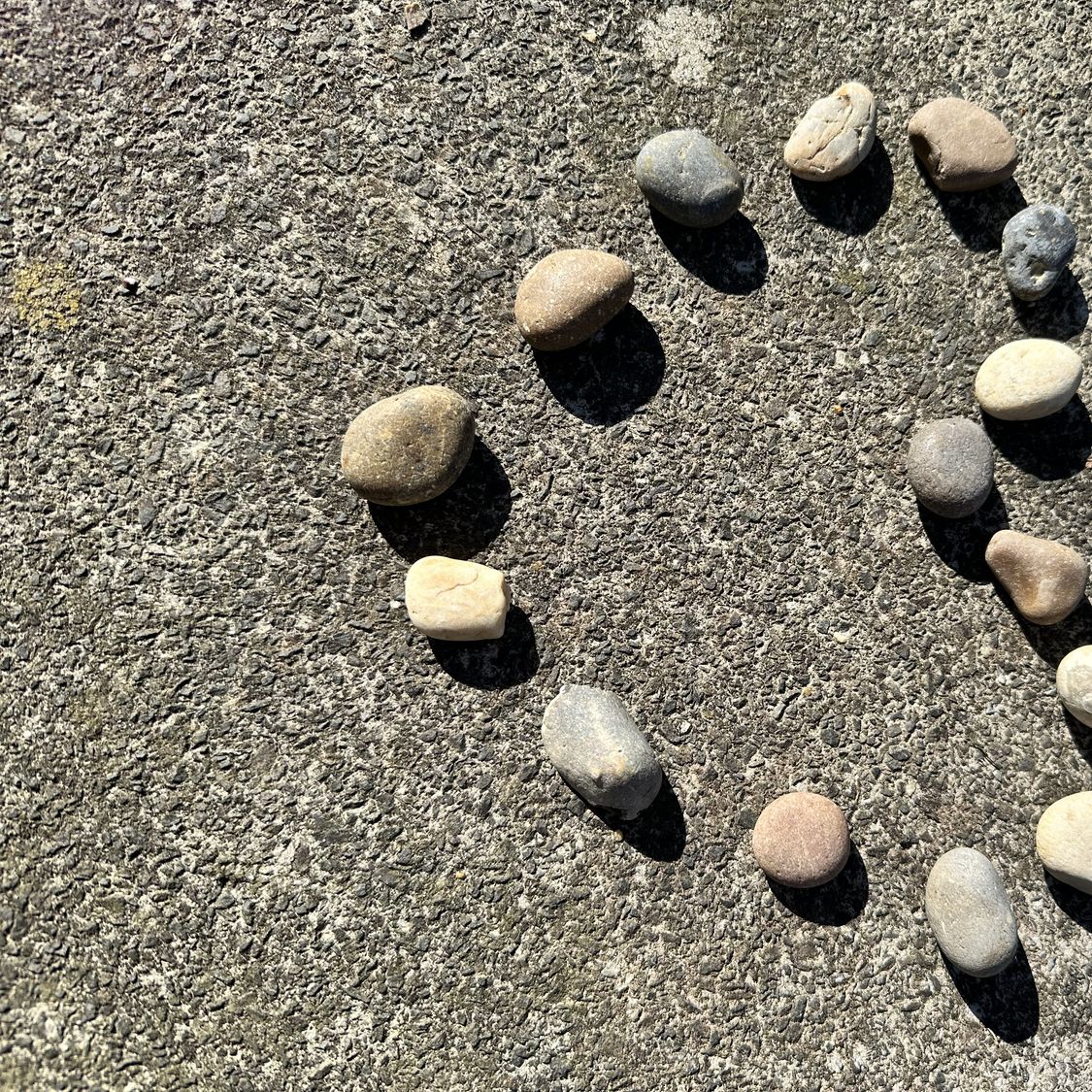 Małe kamienie ułożone w serce na piasku plaży, symbol randki po 50. roku życia, trwałej relacji i dzielonej miłości.